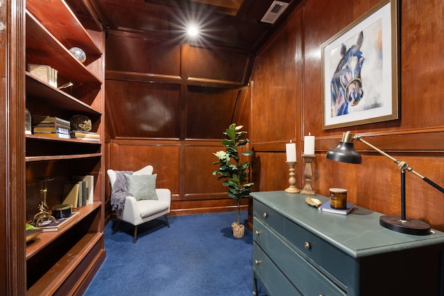 living area featuring dark carpet and wood walls