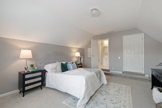 carpeted bedroom with connected bathroom and vaulted ceiling