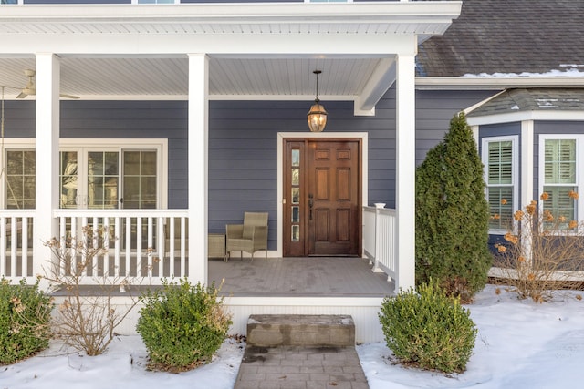 snow covered property entrance with a porch