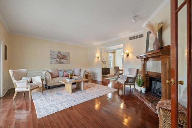 living room with dark wood-type flooring, ornamental molding, and a fireplace