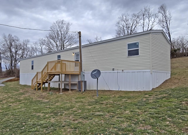 rear view of house featuring a wooden deck and a yard