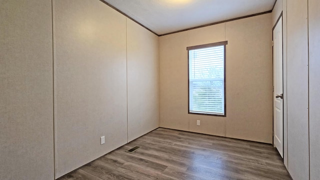 unfurnished room with wood-type flooring and ornamental molding