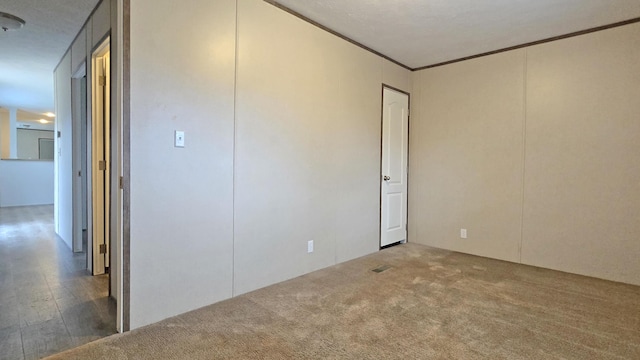 unfurnished room with ornamental molding and carpet