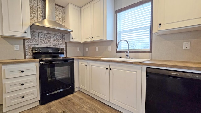 kitchen featuring sink, white cabinets, black appliances, light wood-type flooring, and wall chimney exhaust hood