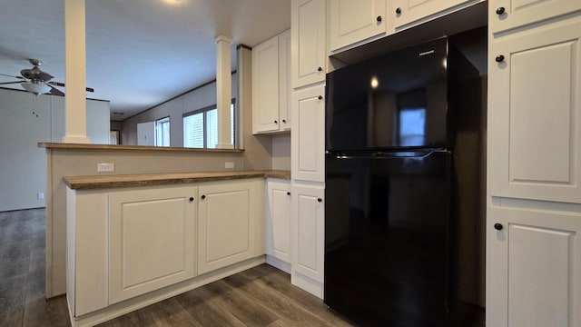 kitchen with black refrigerator, dark hardwood / wood-style flooring, kitchen peninsula, ceiling fan, and white cabinets