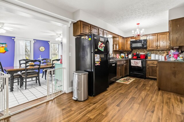 kitchen with sink, ceiling fan with notable chandelier, dark hardwood / wood-style flooring, and black appliances