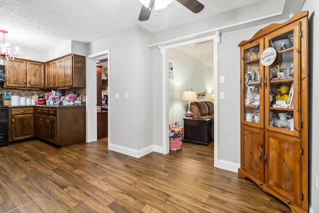 kitchen with dark hardwood / wood-style flooring, backsplash, ceiling fan with notable chandelier, and a textured ceiling