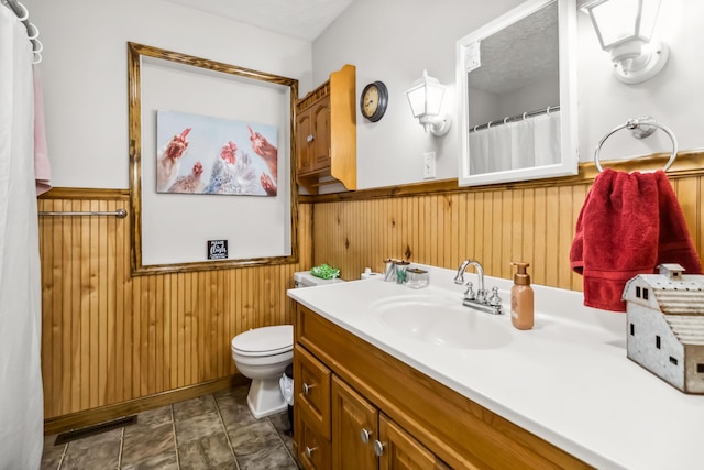 bathroom with vanity, a textured ceiling, wooden walls, and toilet