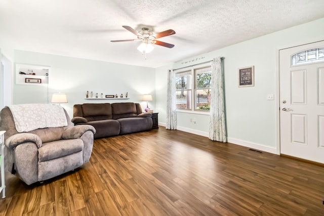 living room with ceiling fan, dark wood-type flooring, and a textured ceiling