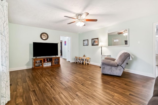 living room with a textured ceiling, dark wood-type flooring, and ceiling fan