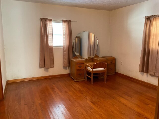 bedroom with baseboards, light wood finished floors, and a textured ceiling
