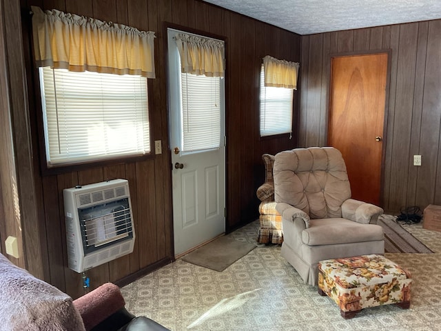 sitting room with a textured ceiling, heating unit, and wood walls