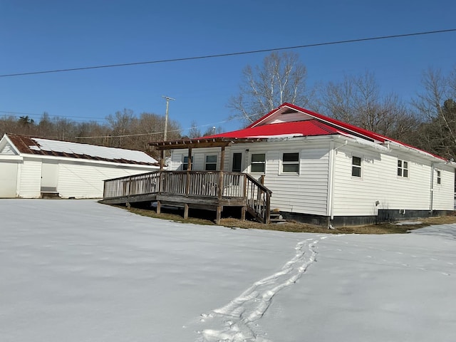 snow covered house with an outbuilding and a deck