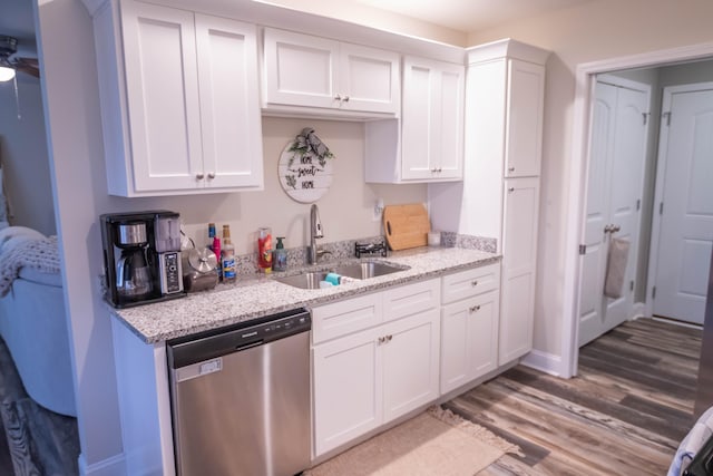 kitchen featuring dishwasher, sink, white cabinets, and light stone counters