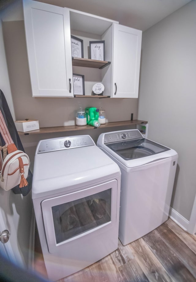 washroom with cabinets, washer and dryer, and light hardwood / wood-style flooring