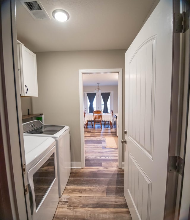 laundry room featuring dark wood-type flooring, cabinets, and washing machine and clothes dryer