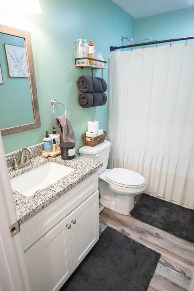 bathroom featuring vanity, hardwood / wood-style flooring, curtained shower, and toilet