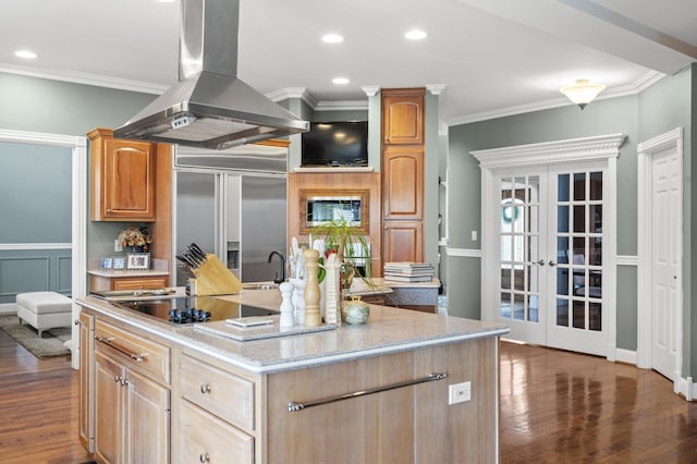 kitchen featuring island exhaust hood, black electric stovetop, an island with sink, french doors, and built in fridge