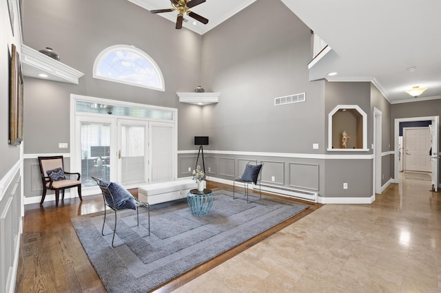 living room featuring a towering ceiling, ornamental molding, and ceiling fan