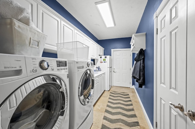 laundry area featuring separate washer and dryer and cabinets