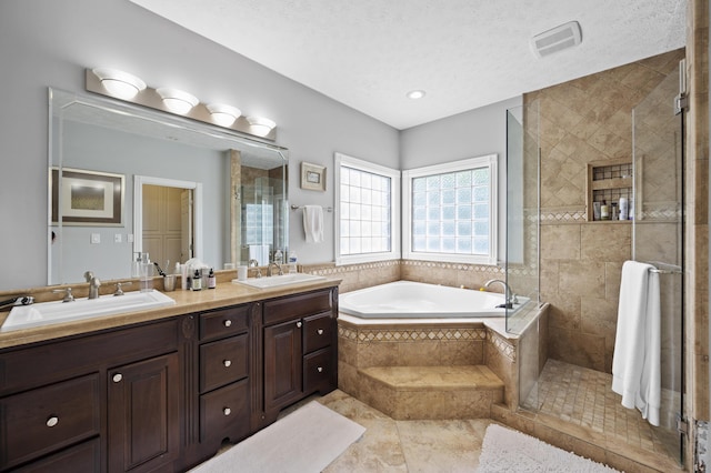 bathroom with plus walk in shower, vanity, and a textured ceiling