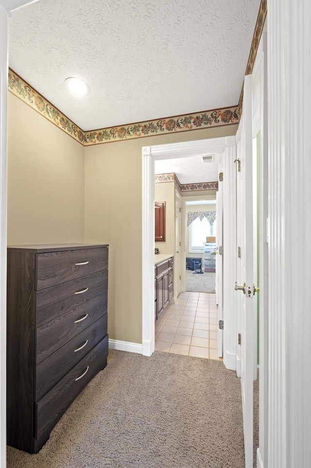 hallway with light colored carpet and a textured ceiling