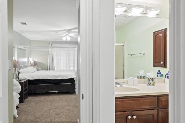 bathroom featuring ceiling fan, vanity, a shower with shower door, and ornamental molding