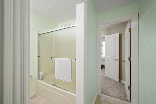 bathroom with enclosed tub / shower combo, tile patterned floors, and a textured ceiling