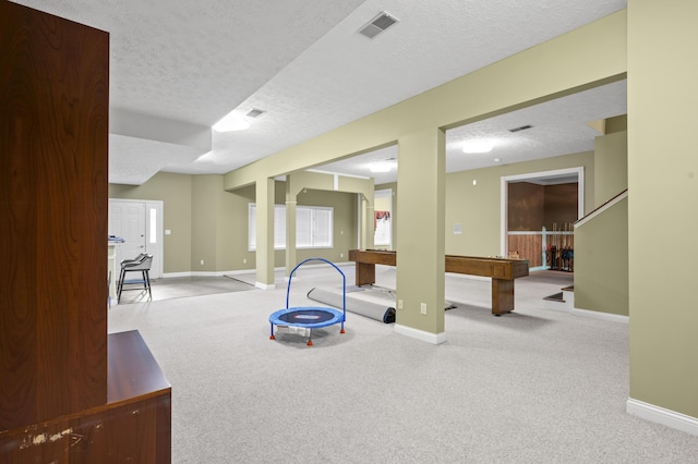 rec room featuring light colored carpet and a textured ceiling