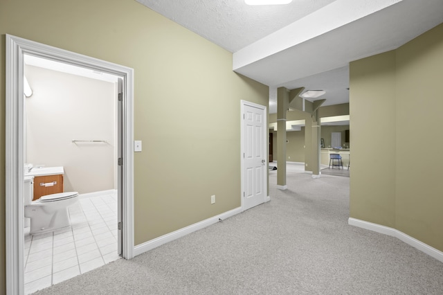 hallway with sink, light colored carpet, and a textured ceiling