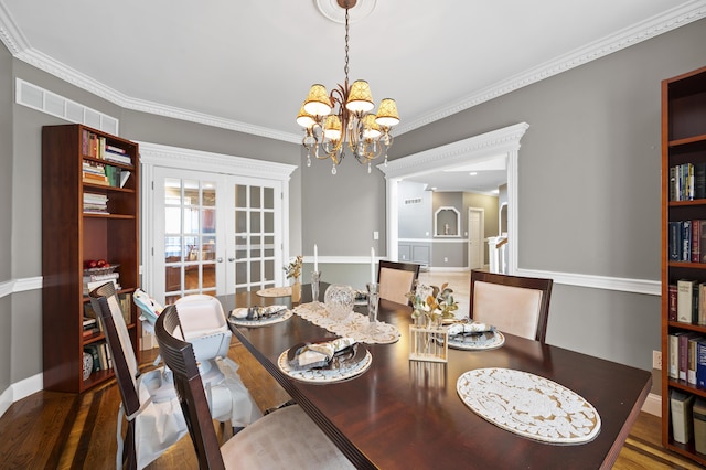 dining room with crown molding, dark wood-type flooring, french doors, and a chandelier