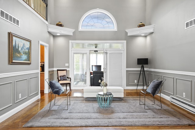 unfurnished room with a high ceiling, a baseboard radiator, and dark hardwood / wood-style flooring