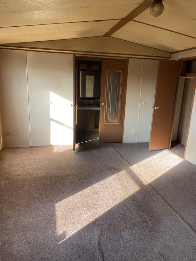 carpeted empty room with lofted ceiling with beams