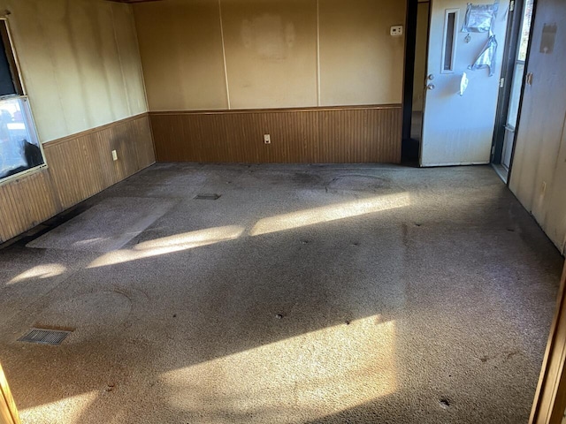 unfurnished room with carpet flooring and wood walls