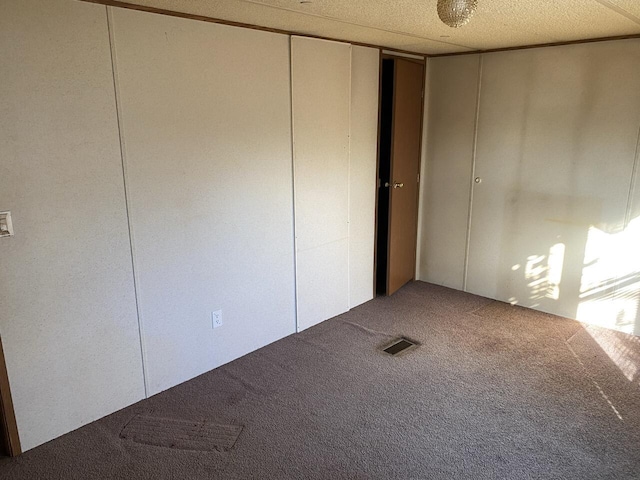 unfurnished bedroom with carpet flooring, a textured ceiling, and a closet