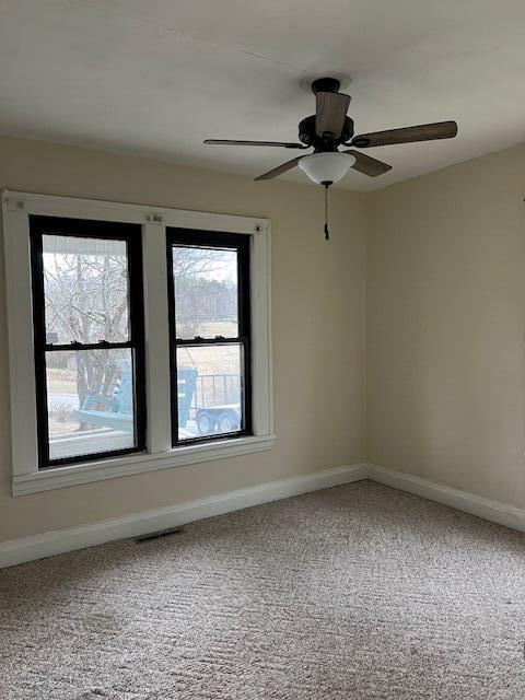 carpeted spare room featuring ceiling fan