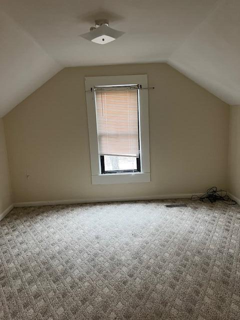 additional living space with vaulted ceiling and light carpet