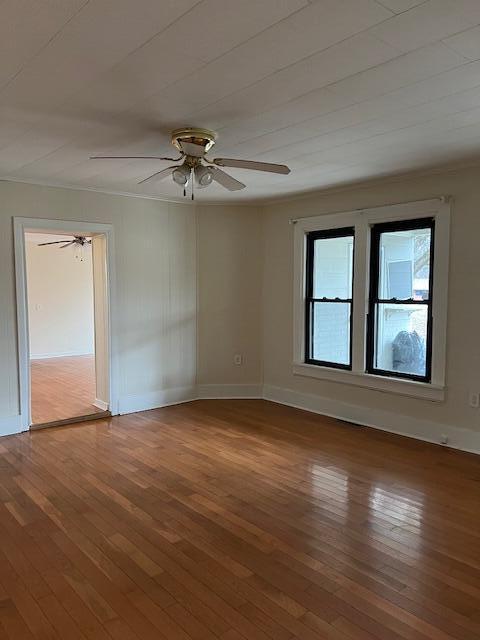 empty room featuring hardwood / wood-style flooring, ornamental molding, and ceiling fan