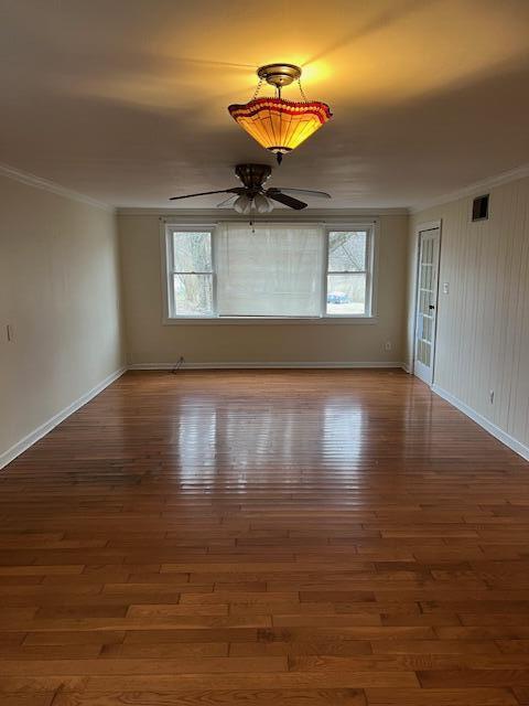 empty room with dark hardwood / wood-style flooring, ornamental molding, and ceiling fan