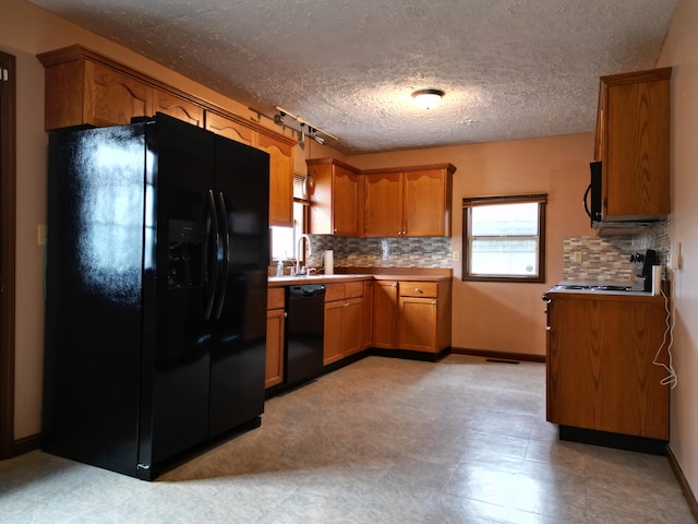 kitchen featuring sink, backsplash, a textured ceiling, and black appliances