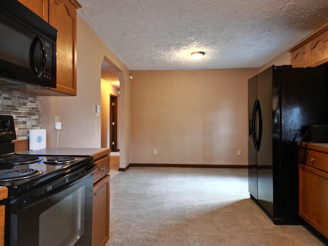 kitchen featuring decorative backsplash, black appliances, and a textured ceiling