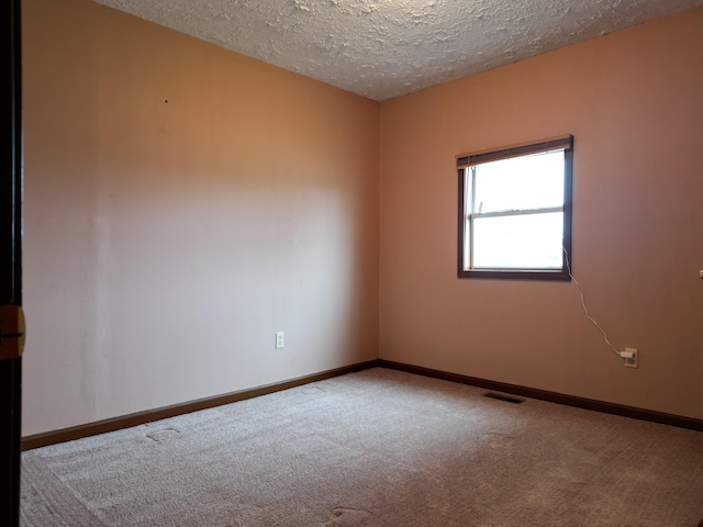 carpeted empty room featuring a textured ceiling