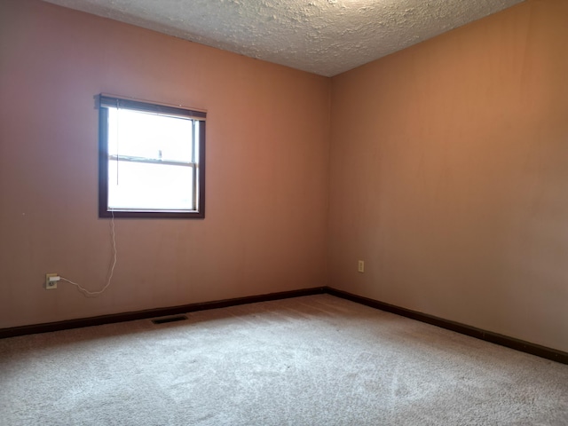 carpeted empty room featuring a textured ceiling