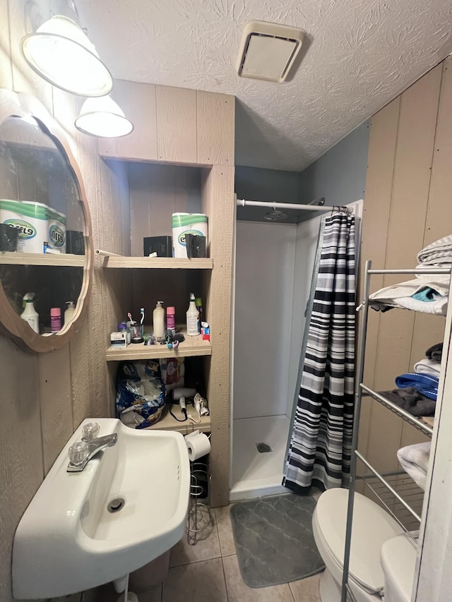 bathroom featuring sink, tile patterned flooring, a textured ceiling, curtained shower, and toilet