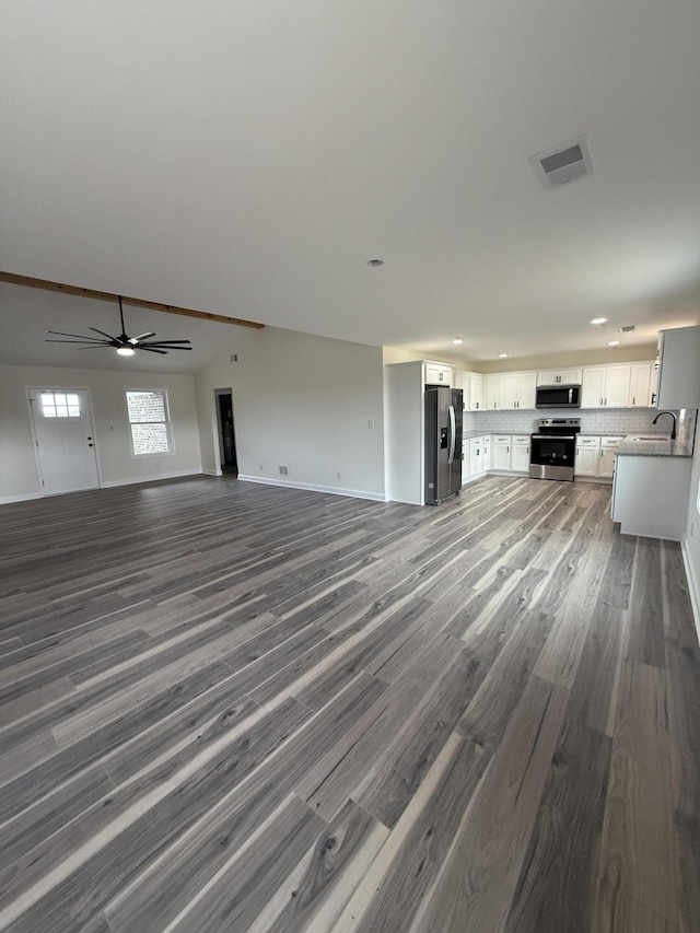 unfurnished living room featuring sink, dark wood-type flooring, and ceiling fan