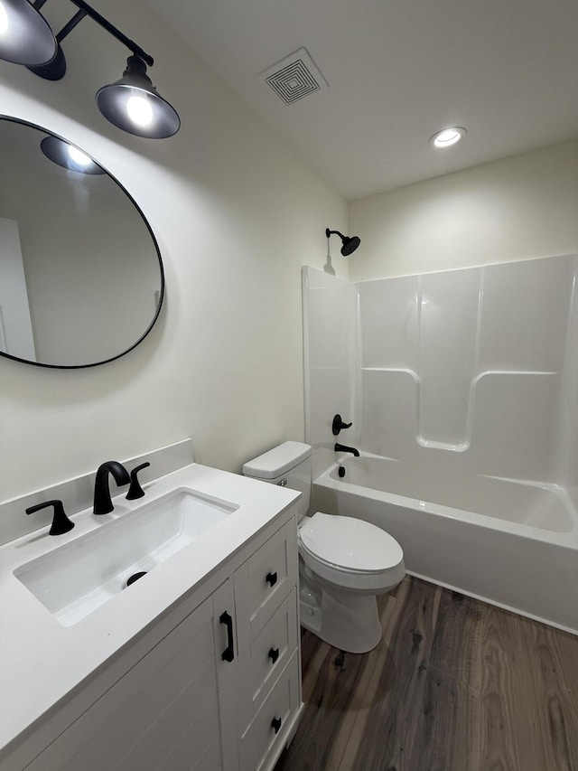 full bathroom with hardwood / wood-style flooring, vanity, tub / shower combination, and toilet