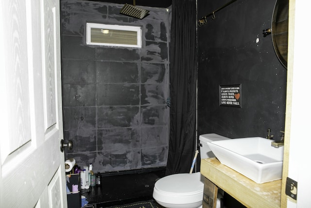 bathroom featuring vanity, a tile shower, and toilet