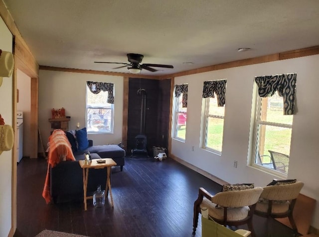 living room with dark hardwood / wood-style flooring, ceiling fan, and a wood stove