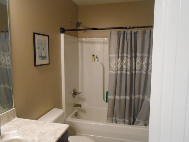 full bathroom with shower / tub combo with curtain, vanity, and toilet