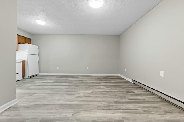 empty room featuring a baseboard heating unit, a textured ceiling, and light hardwood / wood-style flooring